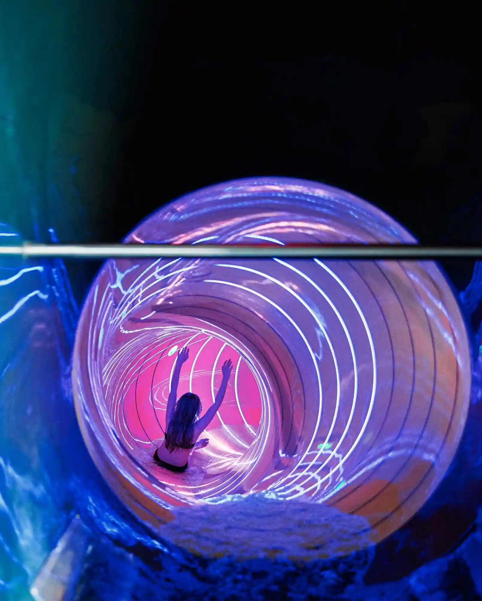 Mädchen rutscht eine neon pink-violette Rutsche mit hinunter.