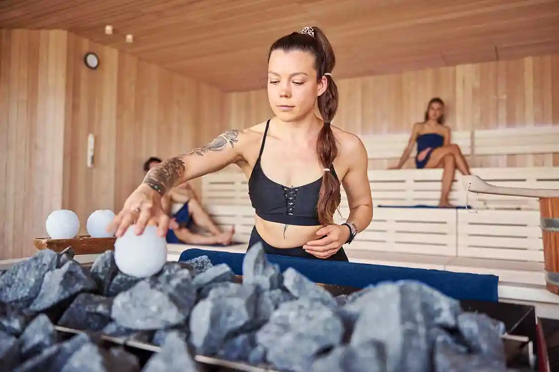 Eine Frau macht in der Panorama Sauna einen Aufguss mit Eisbällen