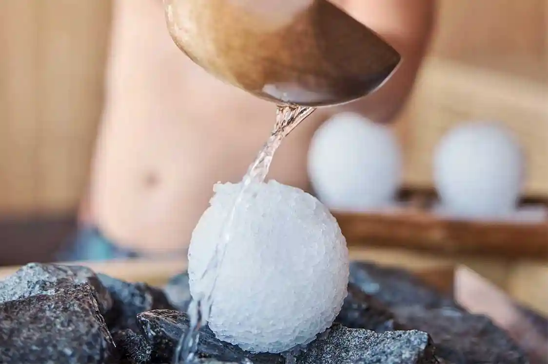 Ein Mann bereitet mit Eis und Wasser einen entspannenden Aufguss in der Sauna vor