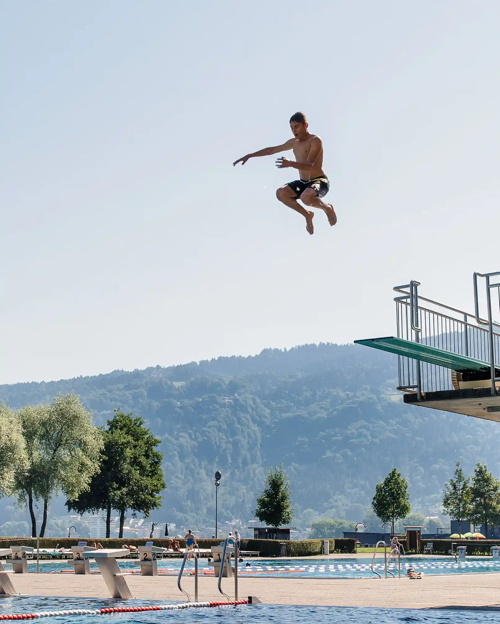 Momentaufnahme eines Jungen im Sprung von einem Sprungbrett