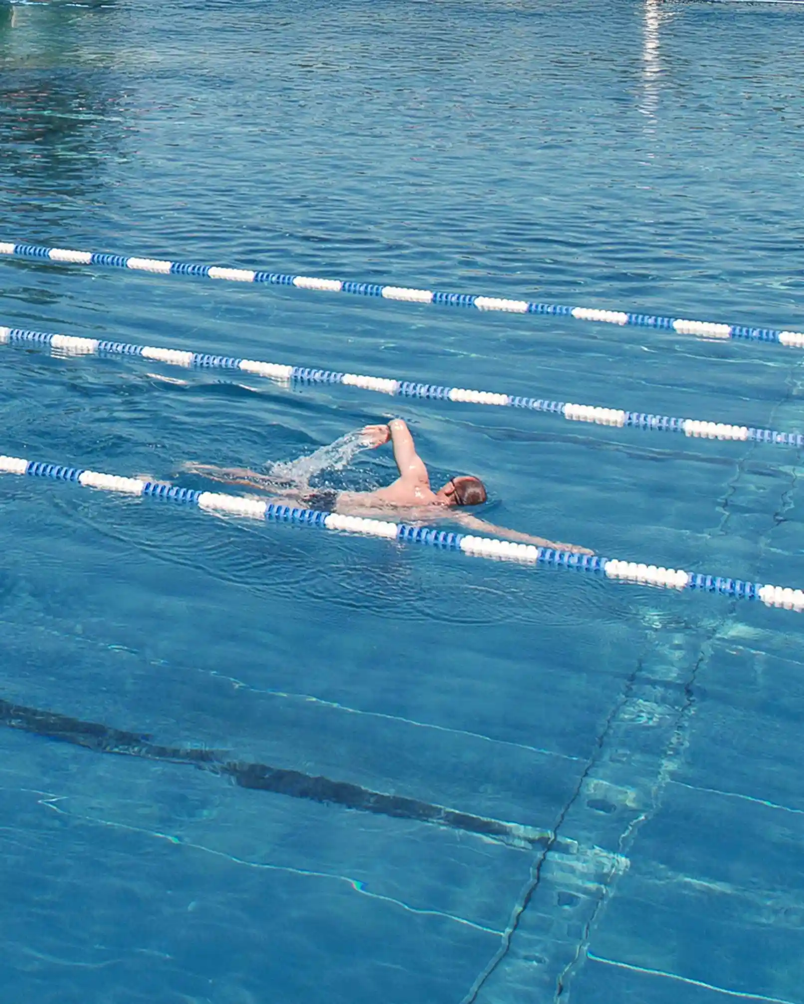 Ein Mann zieht seine Bahnen im Outdoor-Sportbecken